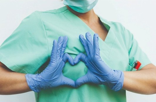 Pflegekraft formt mit den Händen ein Herz